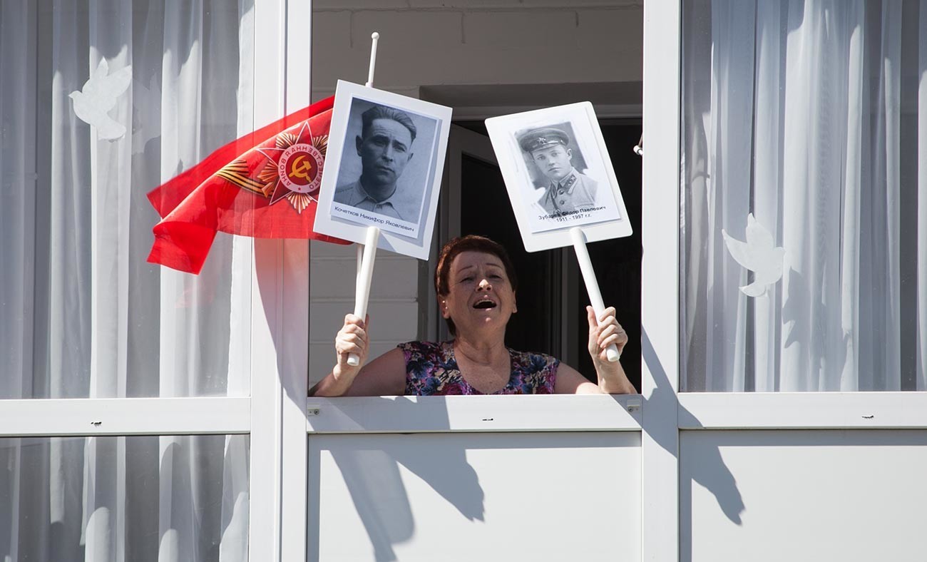 Жителка на Тјумењ со портрети на ветерани на Втората светска војна пее песни од воените години со учесници во акцијата „Парада дома“.

