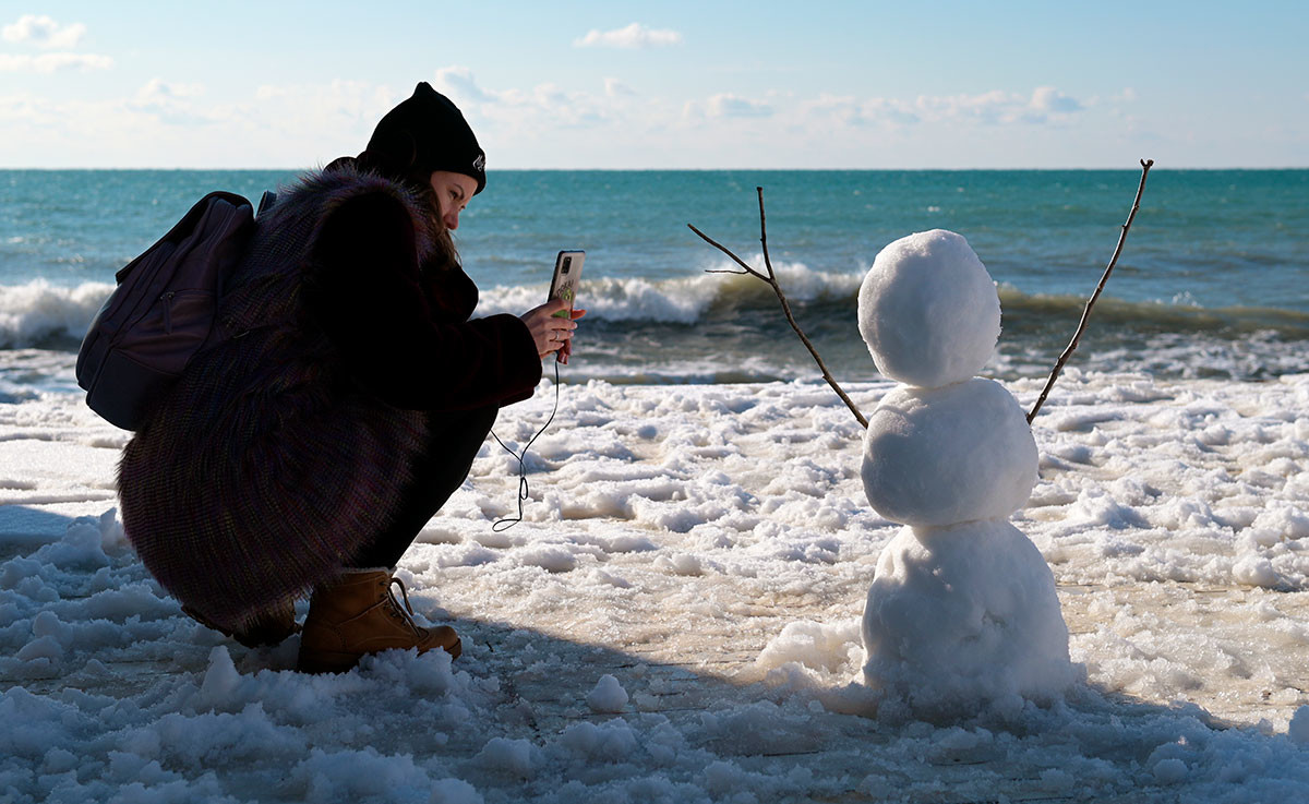 ソチのビーチで雪達磨を撮影している女性