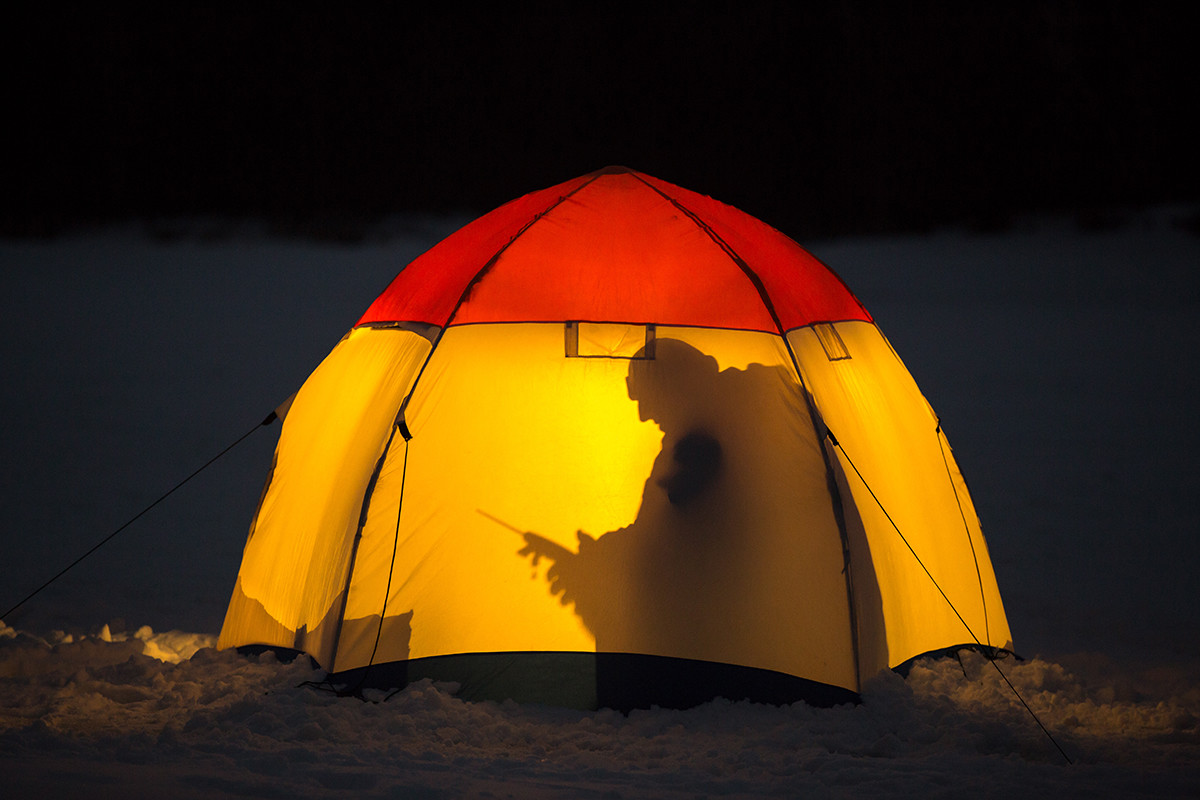 Seorang pria tengah memancing di es dari dalam tenda di Moskovskaya Oblast.