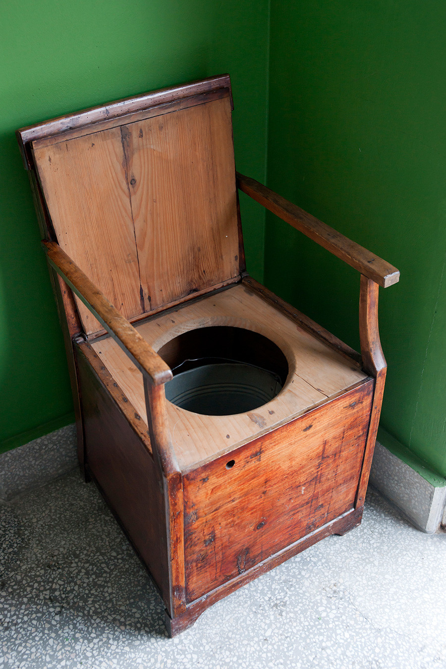 Vintage toilet made of wooden armchair and bucket.