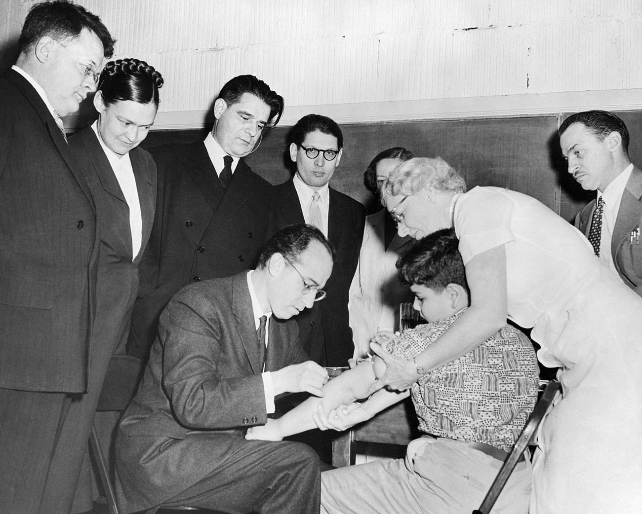 Russische Wissenschaftler beobachten während ihres Besuches in den USA, wie Dr. Jonas Salk einem Kind eine Dosis seines Impfstoffs gegen Kinderlähmung verabreicht.