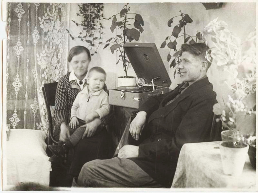 Le meilleur métallurgiste-stakhanoviste (travailleur exemplaire) de matériaux réfractaires du Combinat métallurgique de Magnitogorsk V. Bardakov et sa famille écoutent un gramophone dans leur appartement, 1936