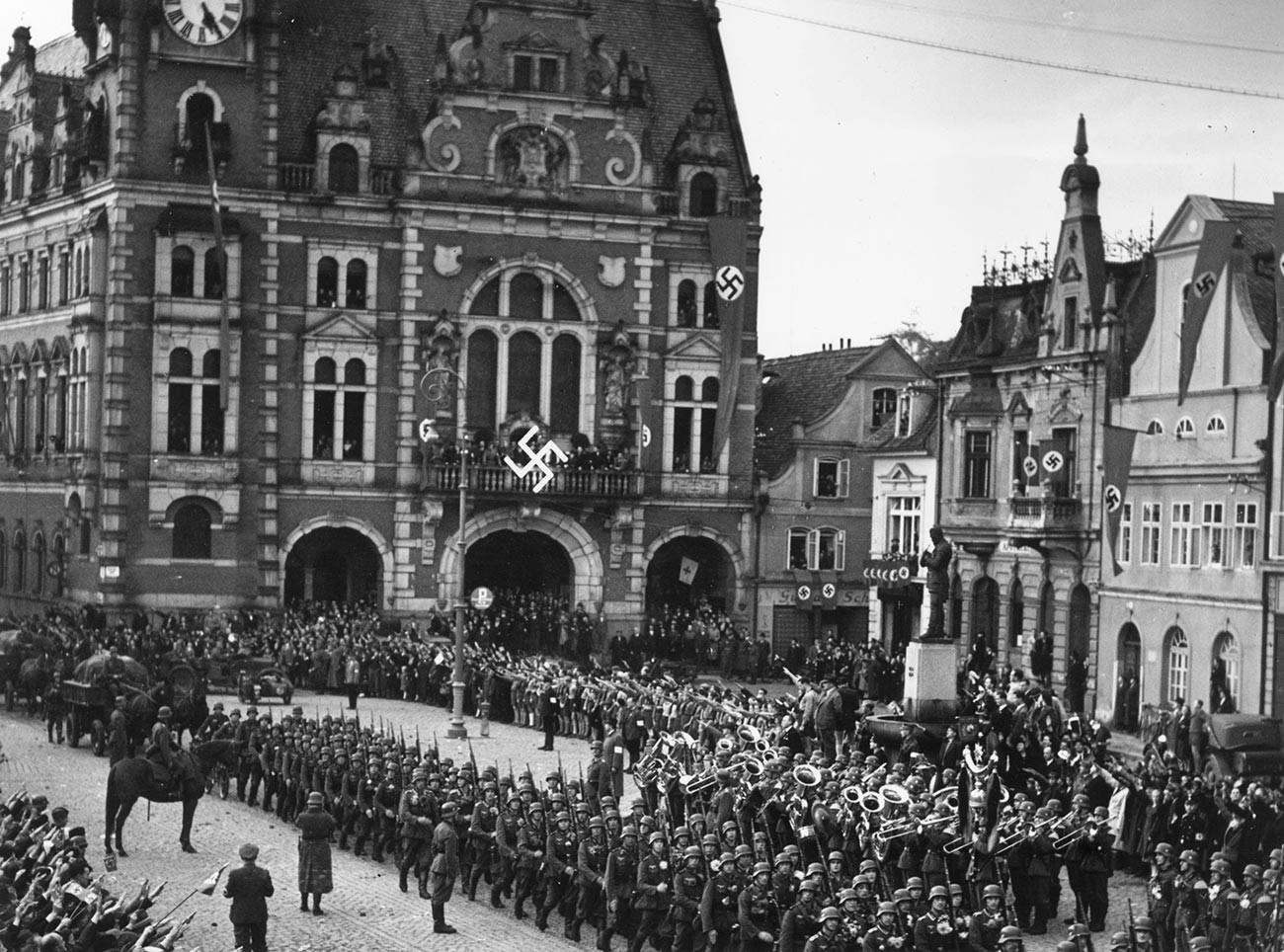 Troops of the German army march into Czechoslovak territory and parade in the town square at Rumburk, which has been decorated with swastika banners.