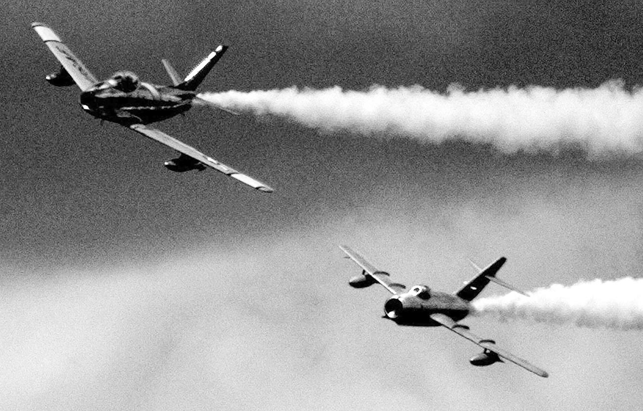 Američki F-86 Sabre (lijevo) iz epohe Korejskog rata, za kojim juri MiG-15 sa sjevernokorejskim obilježjima za vrijeme simulirane bitke na bijenalnom aeromitingu u bazi Zrakoplovne garde SAD-a 