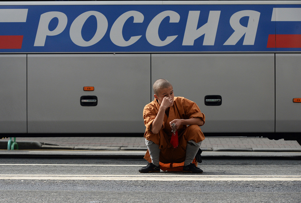 A Chinese musician (from Shaolin monastery) sits squatted waiting for his turn to take the stage in Moscow, during 'Spasskaya Tower' music festival