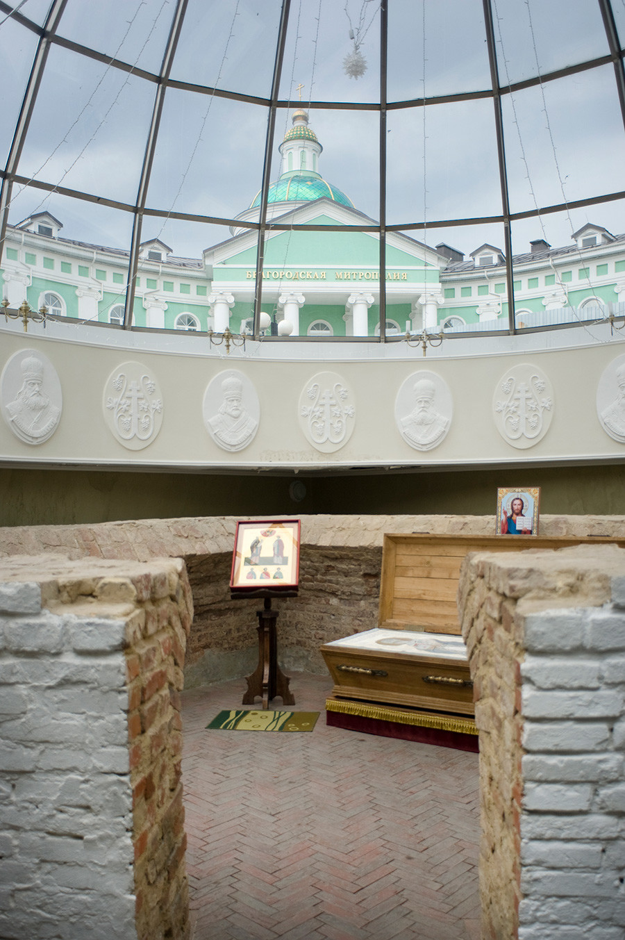Burial crypt of Ioasaph, adjacent to the Chapel of St. Ioasaph. Located at the southwest part of the demolished Trinity Cathedral. Discovered by archeologists in 1911. Upper background: Belgorod Metropolitanate headquarters. June 24, 2015