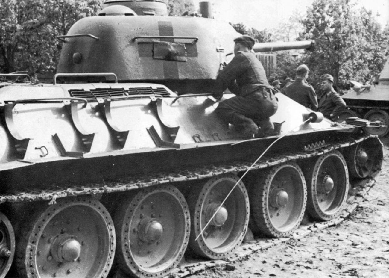 Немачки тенкиста уцртава немачке знаке распознавања на куполу заплењеног совјетског тенка Т-34-76.