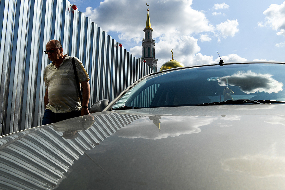 A man walks past a metal fence surrounding a construction site near Moscow's Sobornaya mosque on August 7, 2019