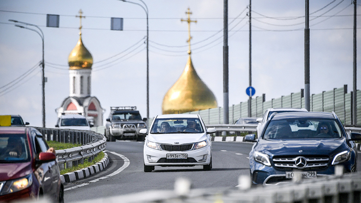 Cars move along a motorway in the Moscow satellite town of Odintsovo on June 17, 2019, as the Cathedral of Saint George the Victorious is seen in the background