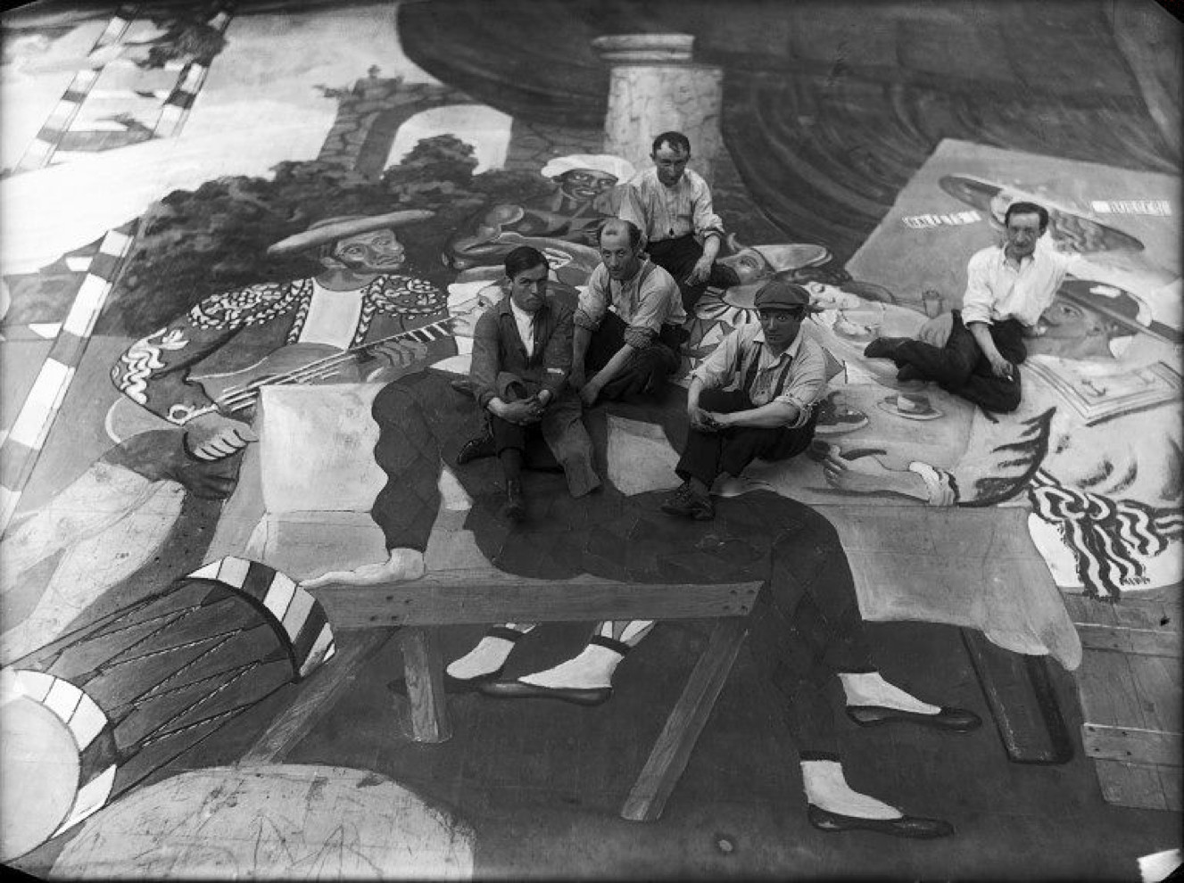 Picasso et les artistes de scène, assis sur un tissu du décor du ballet Parade, au théâtre du Châtelet, Paris, 1917