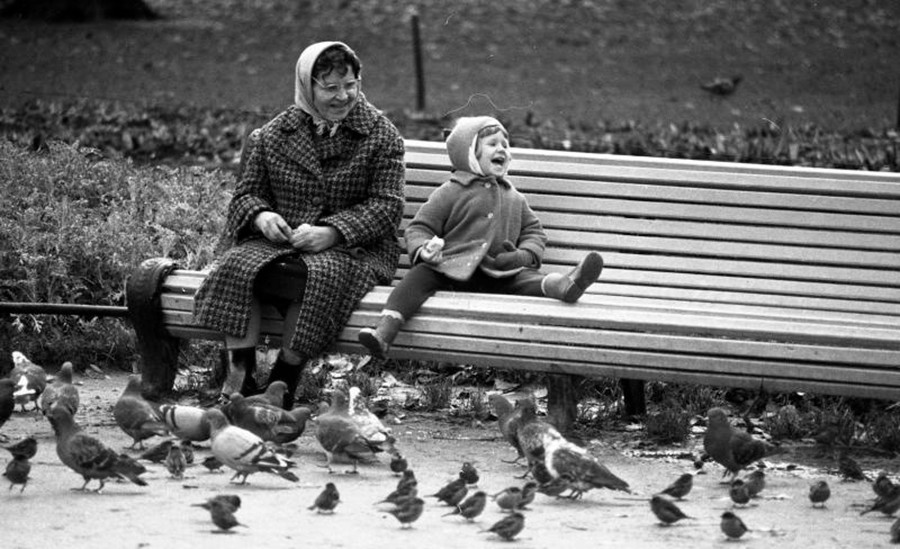 Une grand-mère et sa petite-fille assises sur un banc dans un parc, 1960
