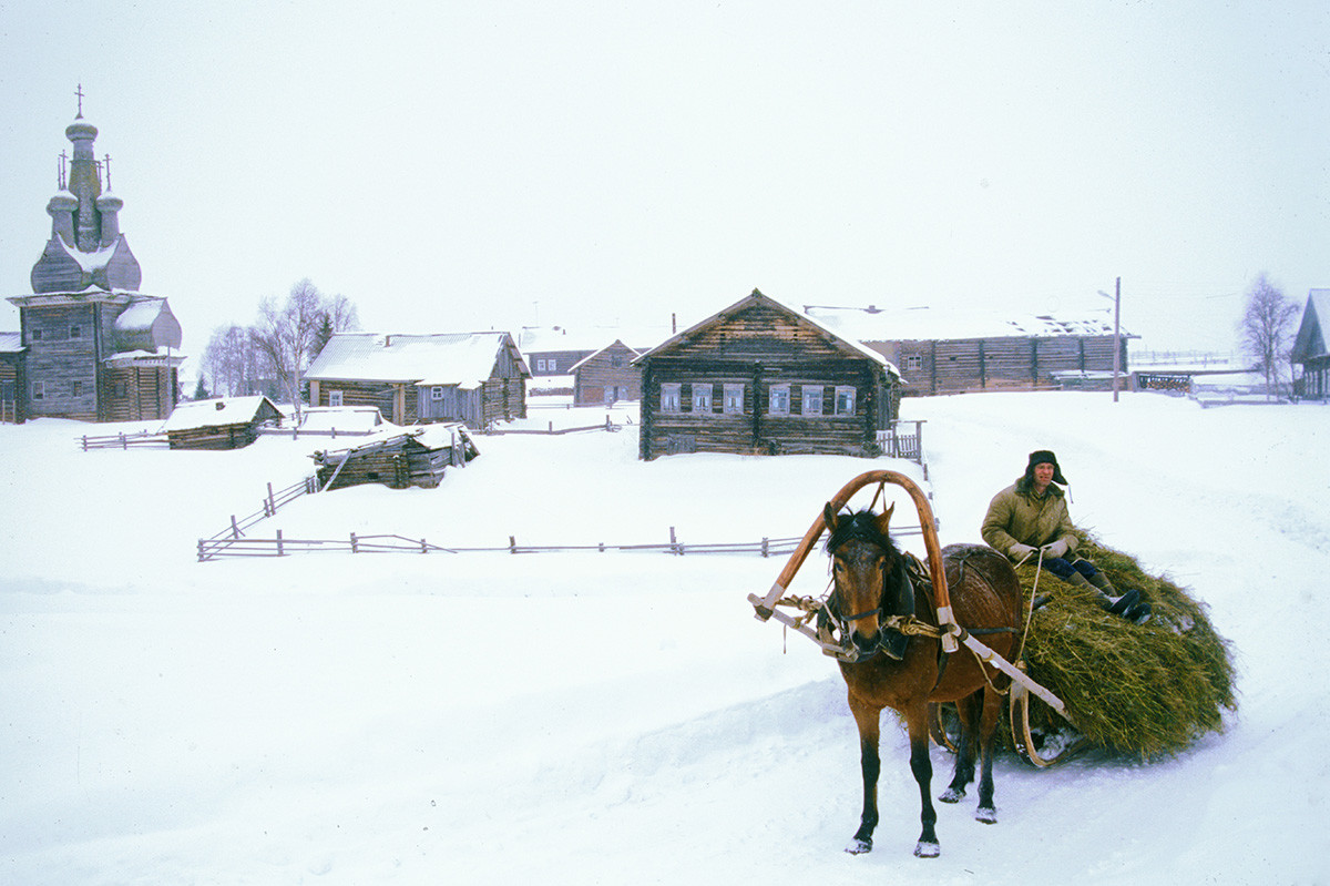 Kimzha village. Church of the Hodegetria Icon, log houses & stables (background). March 7, 2000