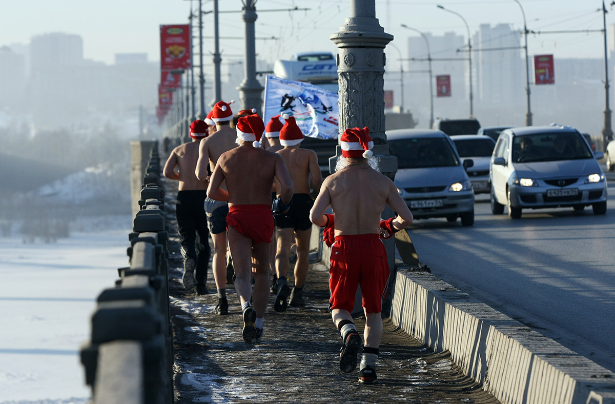 冬のノヴォシビルスクのオビ川でサンタクロースの格好をしてジョギングする男性たち