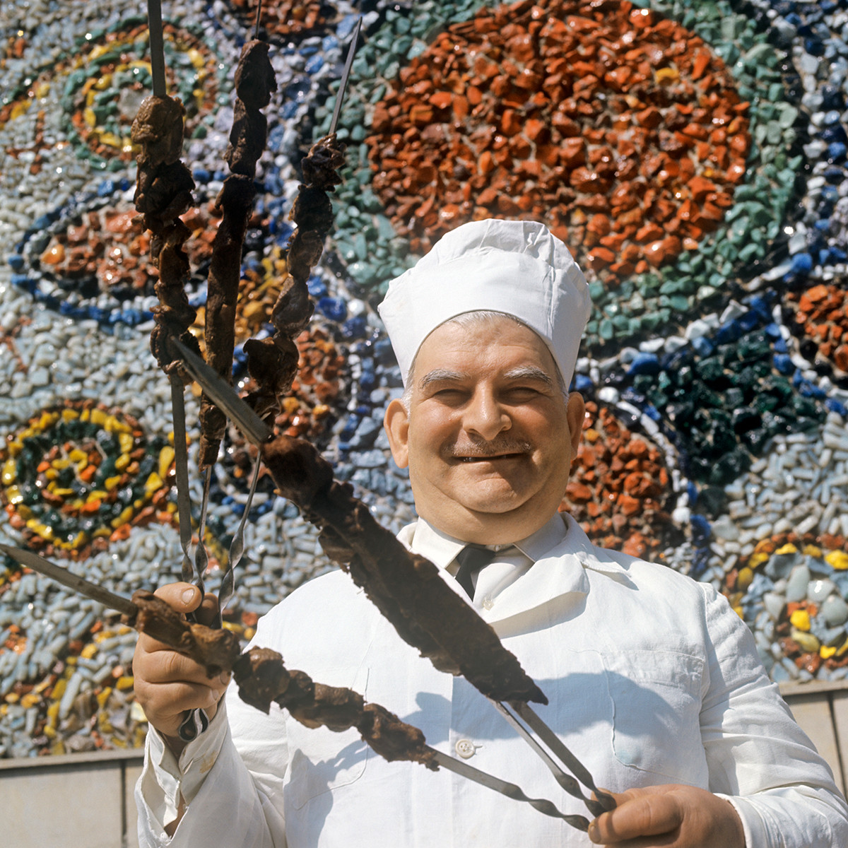 Un cocinero sosteniendo pinchos de shashlik en la RSS de Georgia, 1971