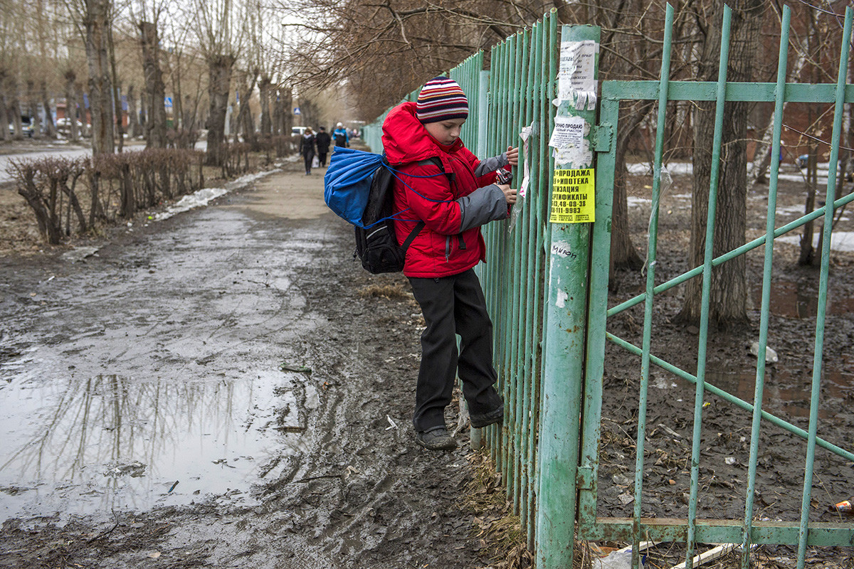A child crosses a puddle on one of the streets of Omsk