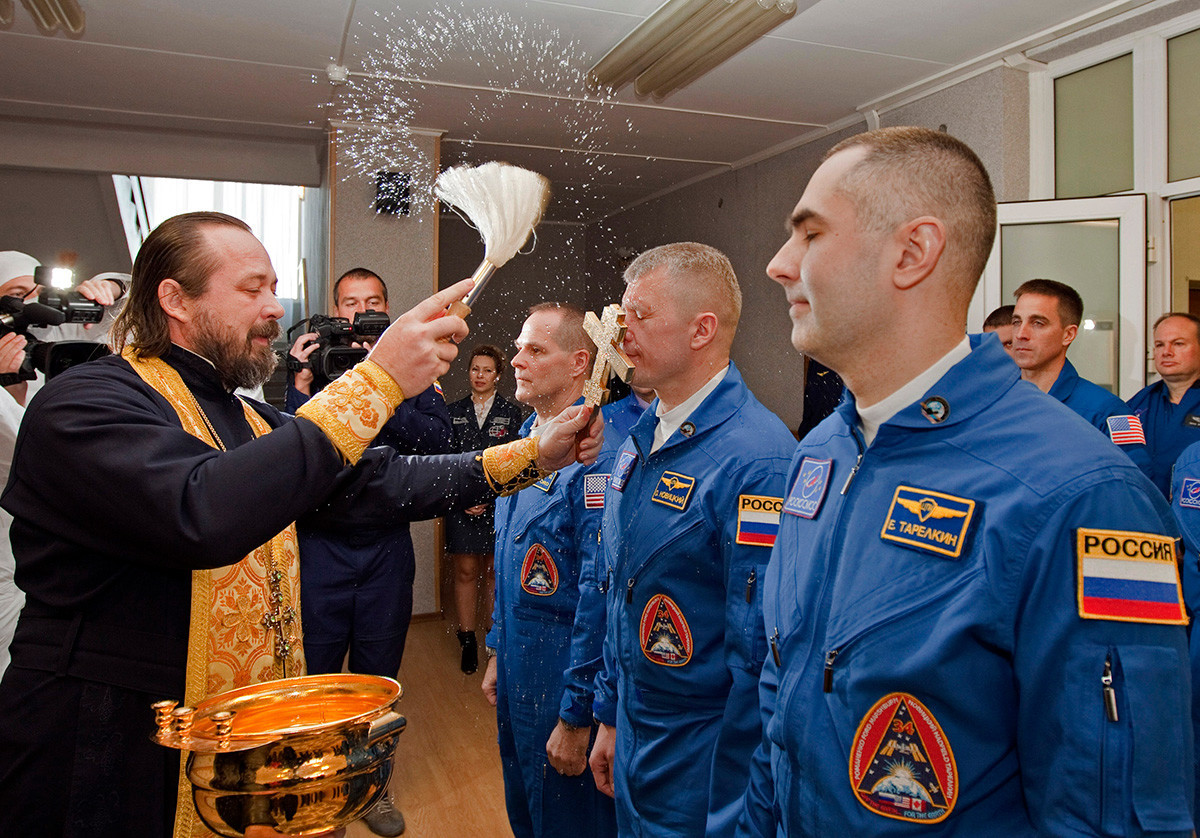 Padre ortodoxo abençoa membros de expedição à ISS (Estação Espacial Internacional): o astronauta norte-americano Kevin Ford (esq.), e dois cosmonautas russos Oleg Novitski (centro) e Evguêni Tarelkin (dir.).