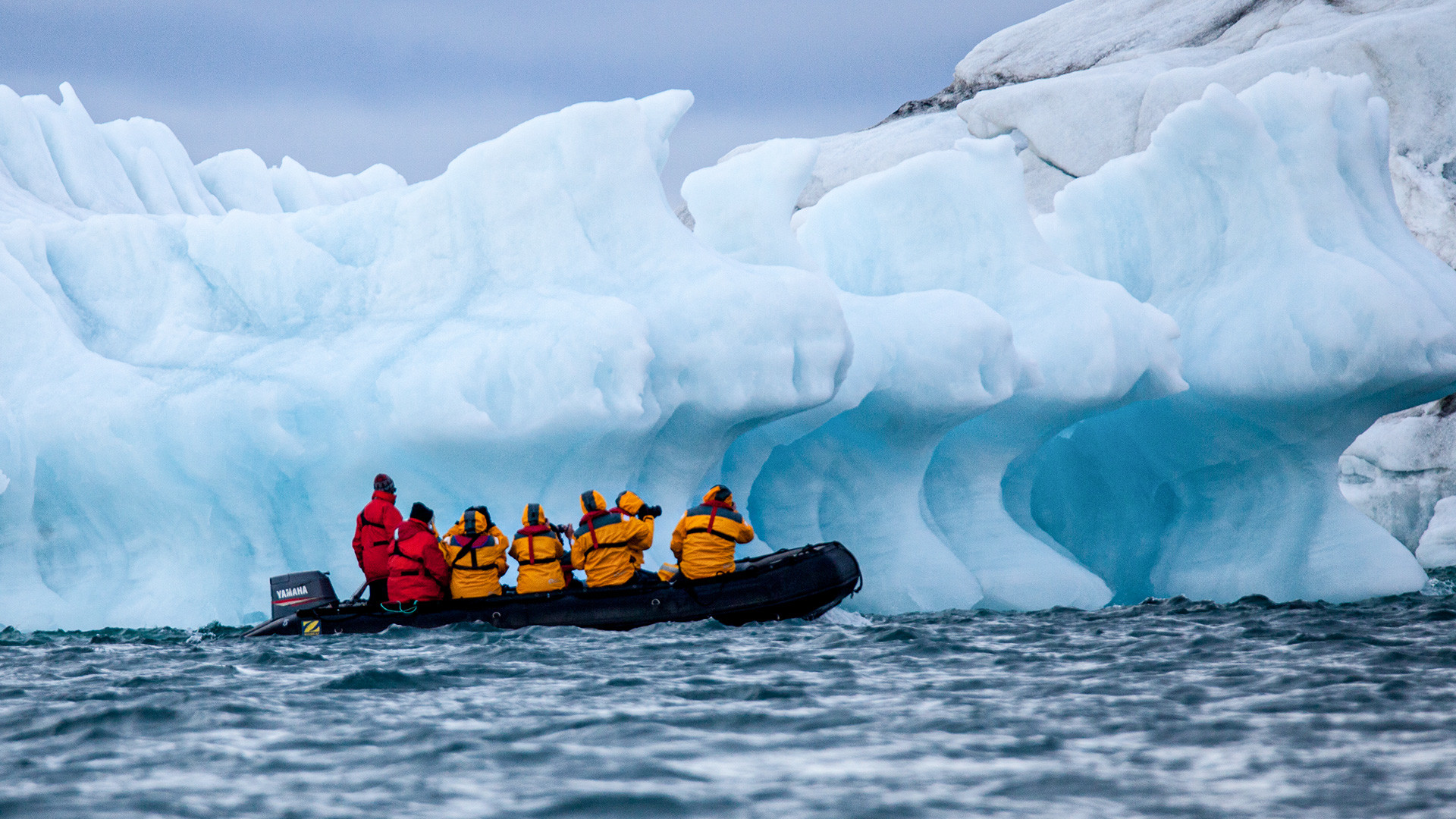 Туристи у чамцу на надувавање испред леденог брега, Арктички океан, Руски Арктик.