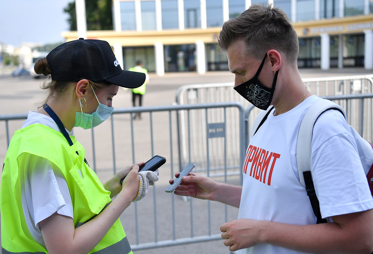 Seorang pria yang mengenakan masker menunjukkan kode QR untuk memverifikasi status COVID-19 di pintu masuk zona penggemar Euro 2020 di Luzhniki, Moskow, Rusia.