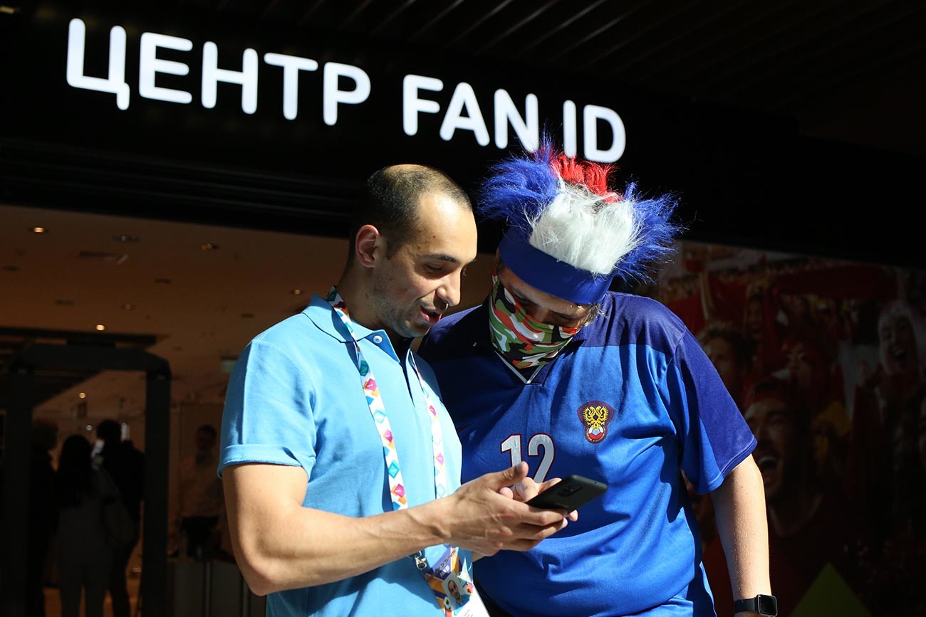 Dua orang suporter di pusat penukaran Fan ID mengecek paspor sebelum turnamen Euro 2020 di pusat perbelanjaan Piterland.