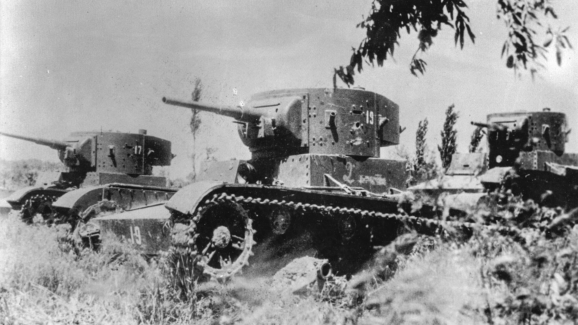 Três tanques leves T-26 fabricados na União Soviética percorrem campo durante batalha na  Guerra Civil Espanhola. 
