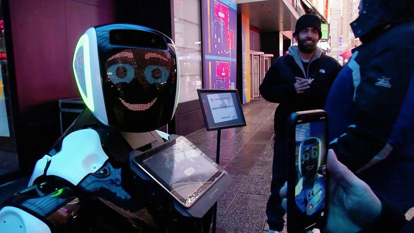 Минувачи на Тајмс Сквер разговараат со роботот „Промобот“, кој ја информира јавноста за симптомите на коронавирусот и спречувањето на неговото ширење. Скриншот. Њујорк.