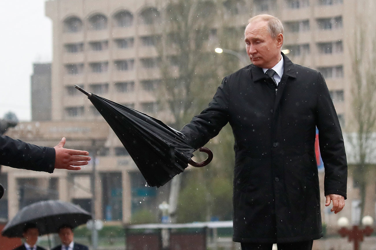 04 - Президентът на Русия Владимир Путин връчва чадър на асистент, докато участва в церемония по поднасяне на венци пред паметника на Вечния огън след разговорите с киргизския си колега Сооронбай Джеенбеков в Бишкек, Киргизстан, 28 март 2019 г.