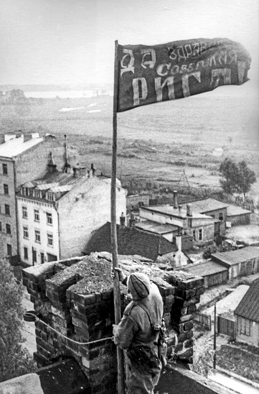 Рига, Летонска ССР, СССР. Војник истиче црвену заставу над градом након његовог ослобађања од немачко-фашистичких освајача током Другог светског рата.