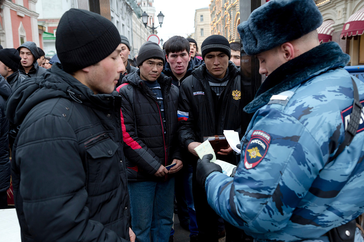 Ein Polizist überprüft Dokumente von Wanderarbeitnehmern aus Zentralasien während einer Einreise zum Roten Platz in Moskau, Russland.