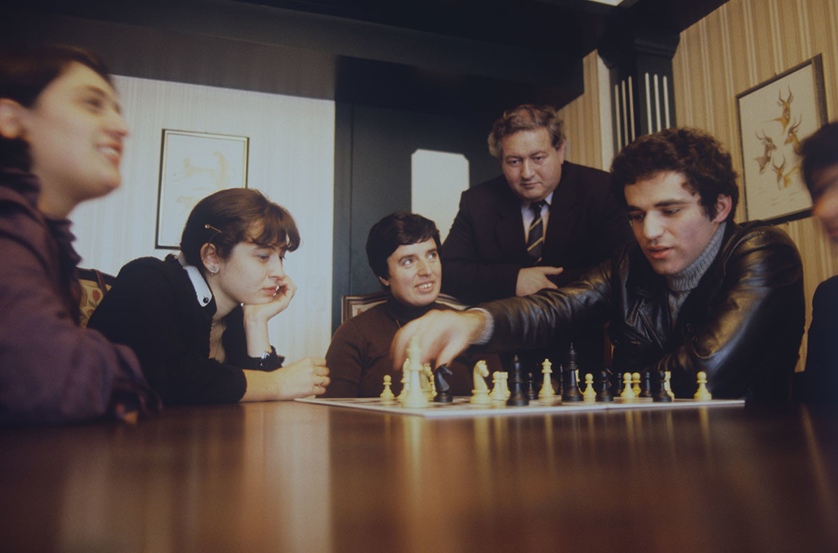 Međunarodni šahovski velemajstor Gari Kasparov razmatra partiju Karpova i Kasparova (II. meč za titulu svjetskog prvaka u šahu 1985.) s gruzijskim šahisticama Majom Čiburdanidze, Nanom Aleksandrijom i Nonom Gaprindašvili (slijeva nadesno). Stoji velemajstor Eduard E. Gufeljd. 