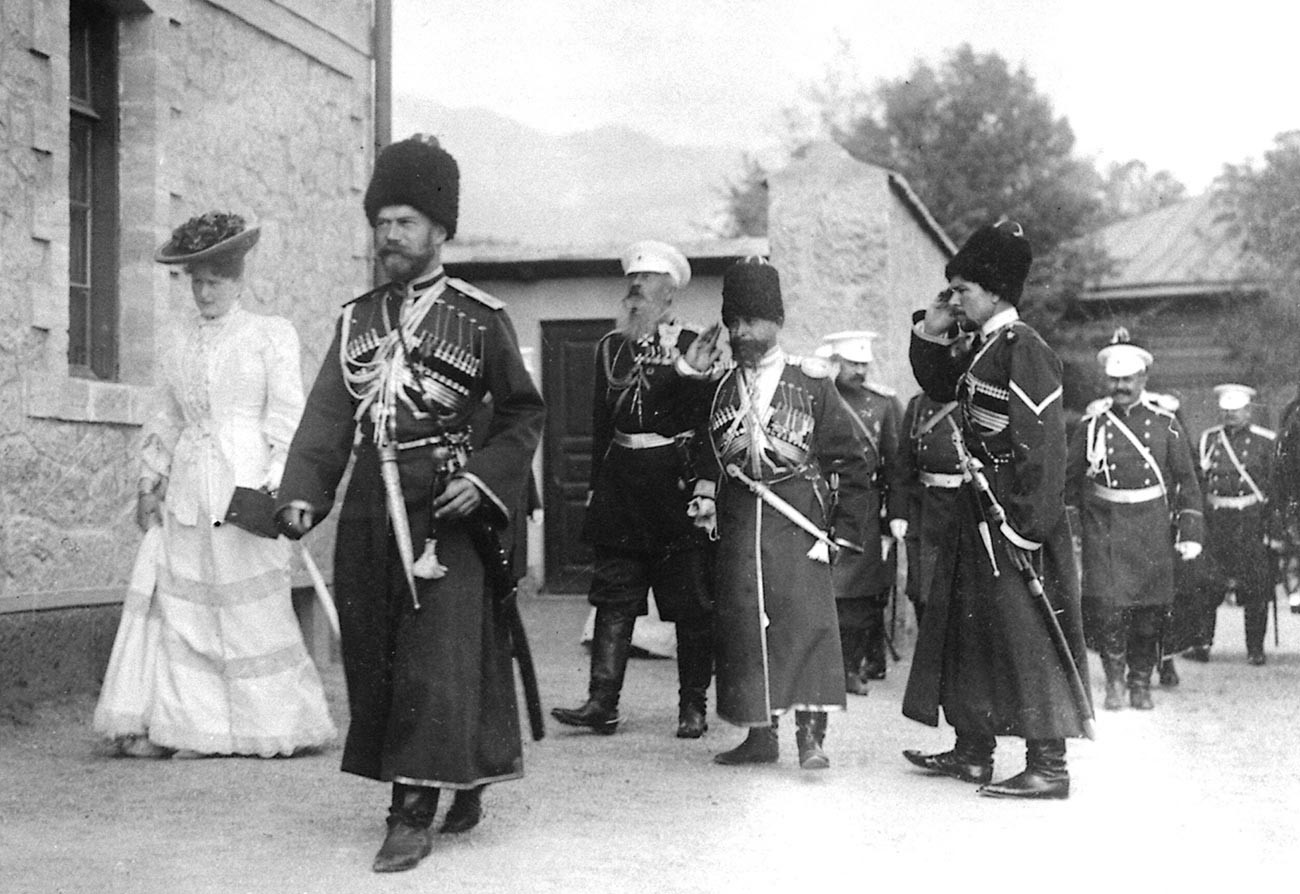 Nikolay II (mengenakan seragam Cossack) dan Aleksandra Fyodorvna diikuti Pengawal Cossack Yang Mulia pada kunjungan di Livadia, Krimea, 1913.
