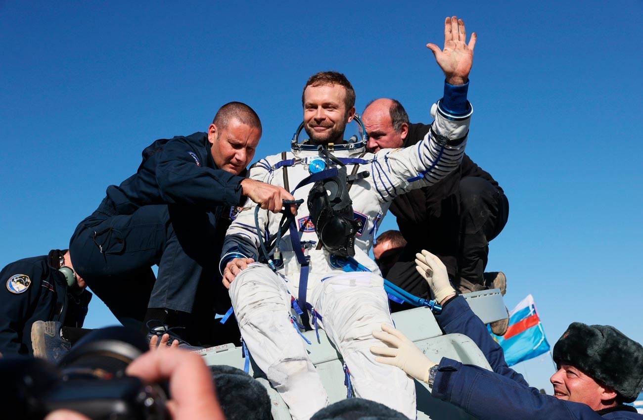 Membro da equipe do filme ‘Vizov’, diretor Klim Chipenko (centro), após descida do módulo de pouso da nave Soyuz MS-18