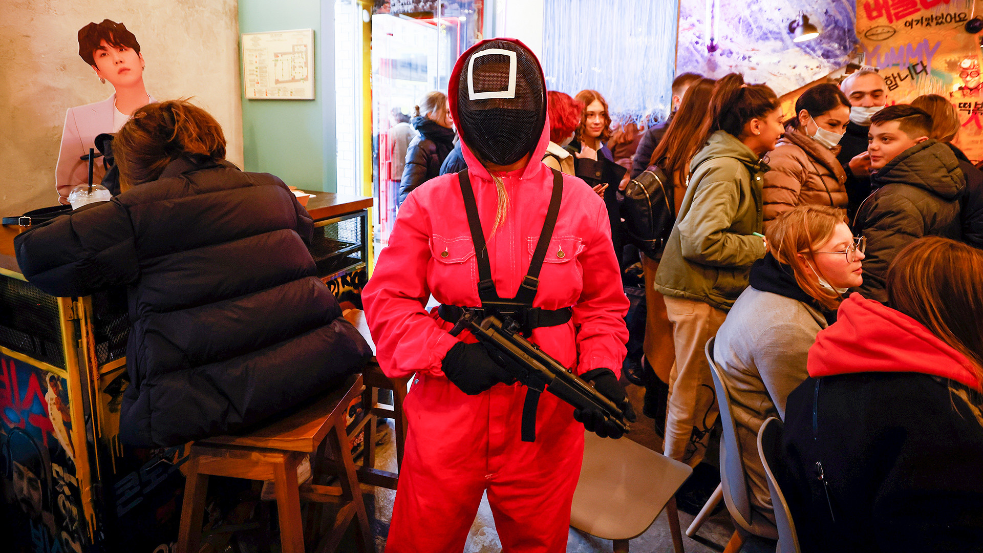 Seorang pelayan kafe Korea Chick O'Rico dengan kostum tokoh dalam film serial “Squid Game” mengarahkan senapan mainan ke seorang pengunjung di Moskow.