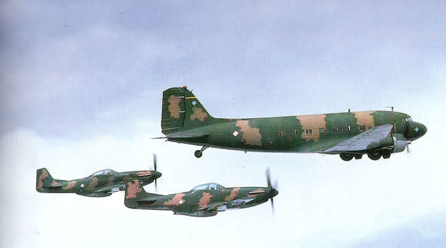 Dos aviones P-51 dominicanos escoltan a un DC-3 del mismo país.