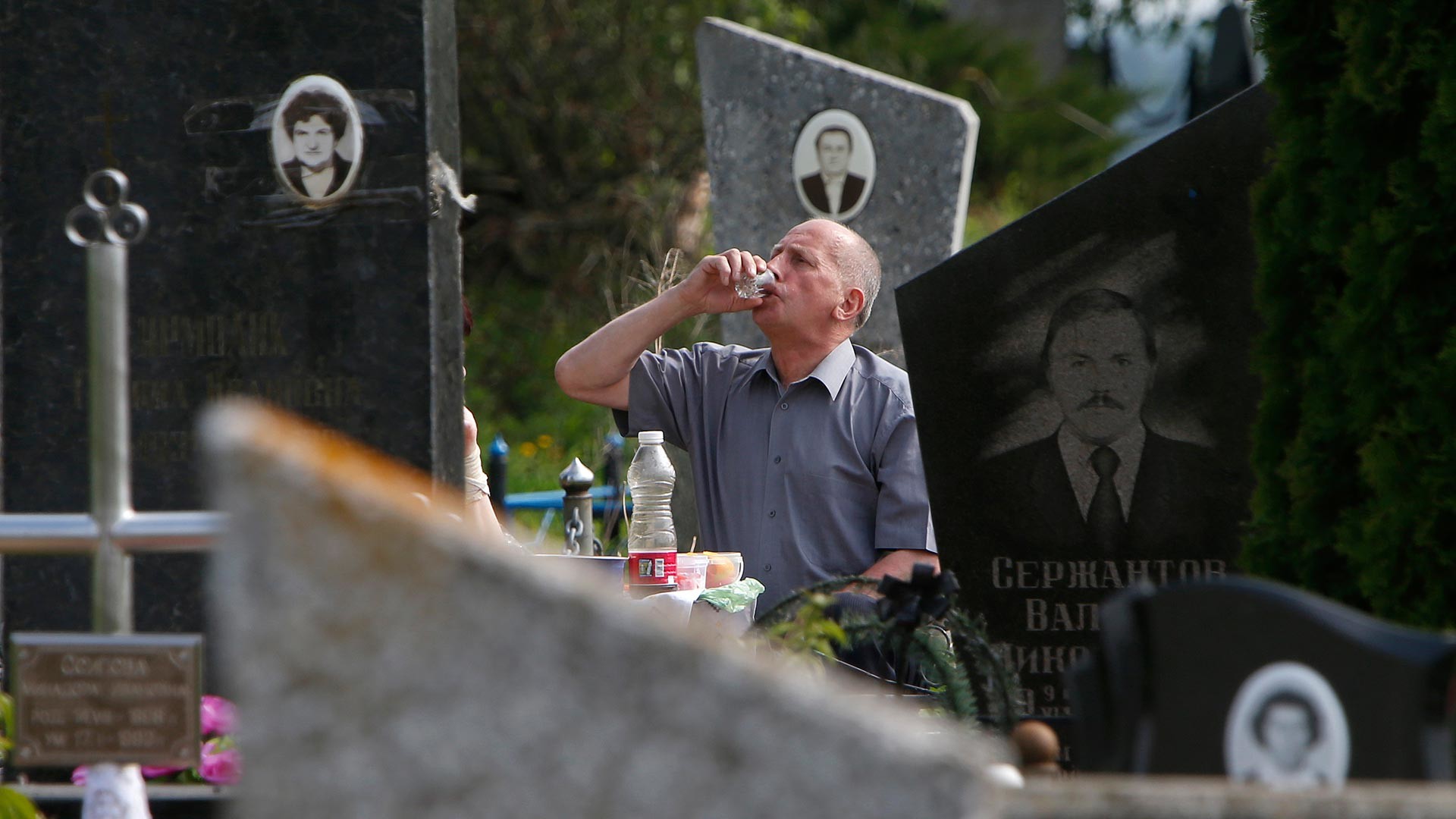 A man drinking on the grave site during Radonitsa, a commemoration holiday.