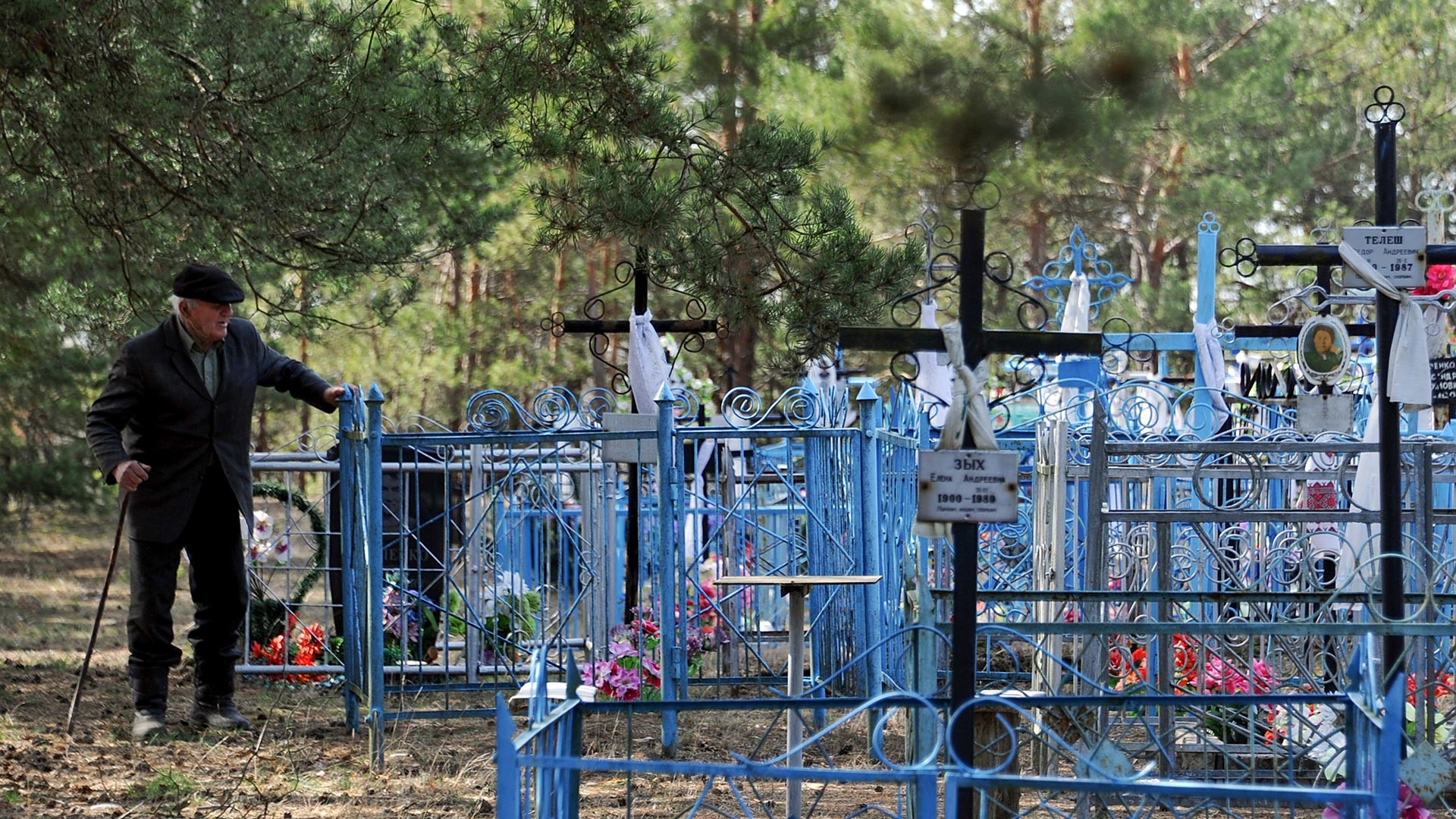 Un anziano tra le tombe di un cimitero russo