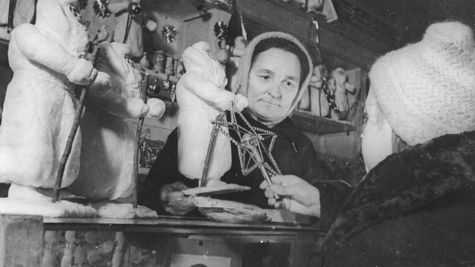 Продавщица отдела игрушек одного из магазинов Ленпромторга К.И. Цыганенко показывает юной покупательнице елочные украшения, 1942 год.
