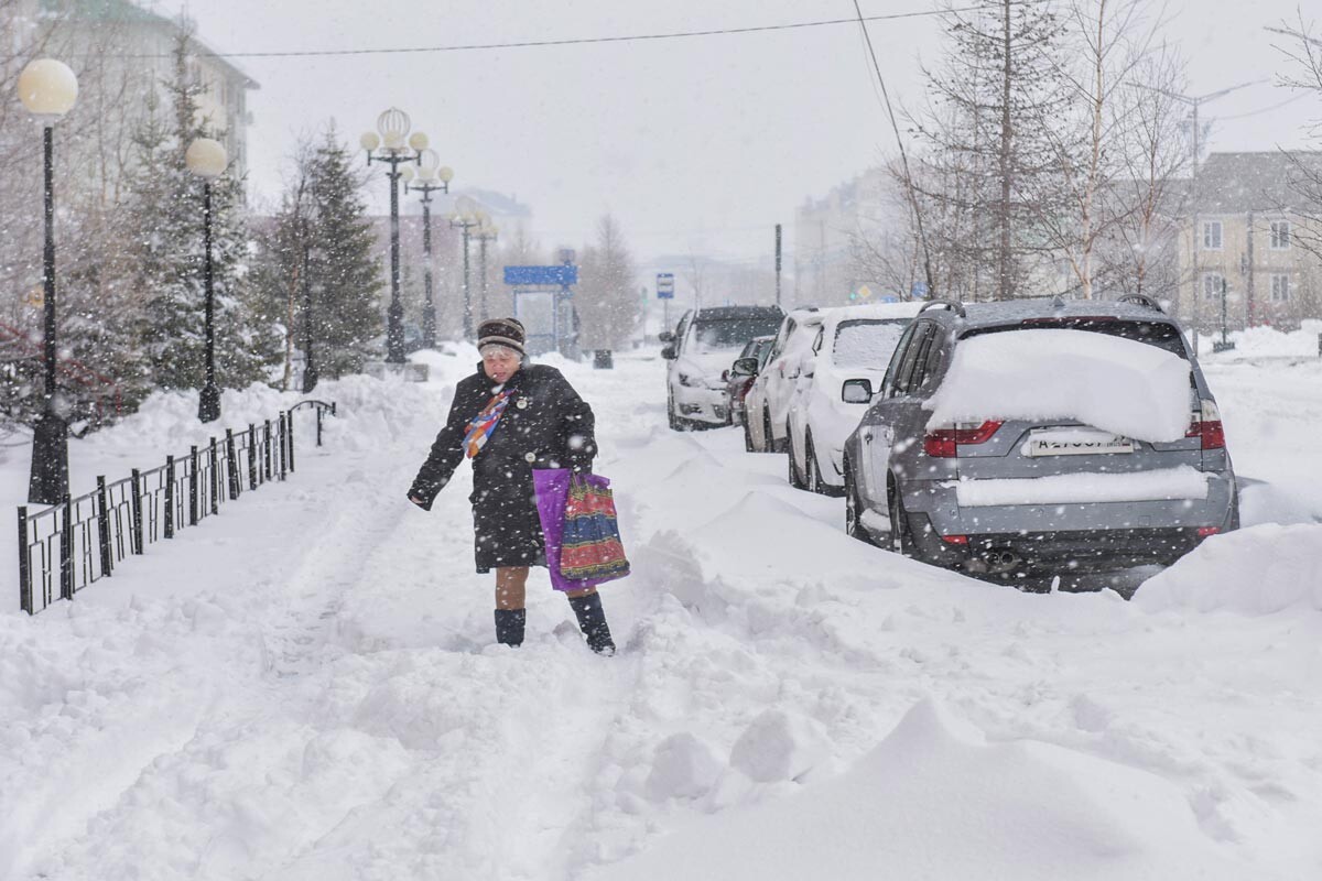 Seorang penduduk lokal berjalan saat hujan salju di Kota Salekhard, 24 Mei 2019.