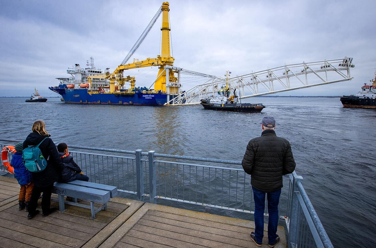Минувачи го гледаат рускиот брод за поставување цевки „Академик Черски“ додека тегначи го тегнат од пристаништето во Балтичкото море. Во последните недели бродот беше опремен со дополнителна опрема во Висмар. Мекленбург – Западна Померанија, Висмар.
