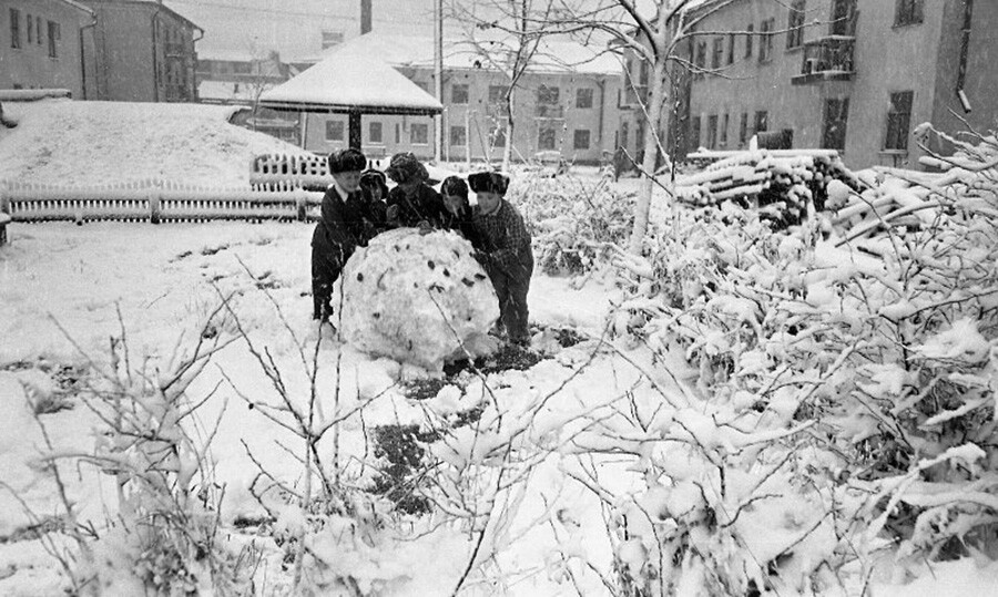 Voici des enfants soviétiques des années 1960 œuvrant ensemble pour faire un énorme bonhomme de neige.