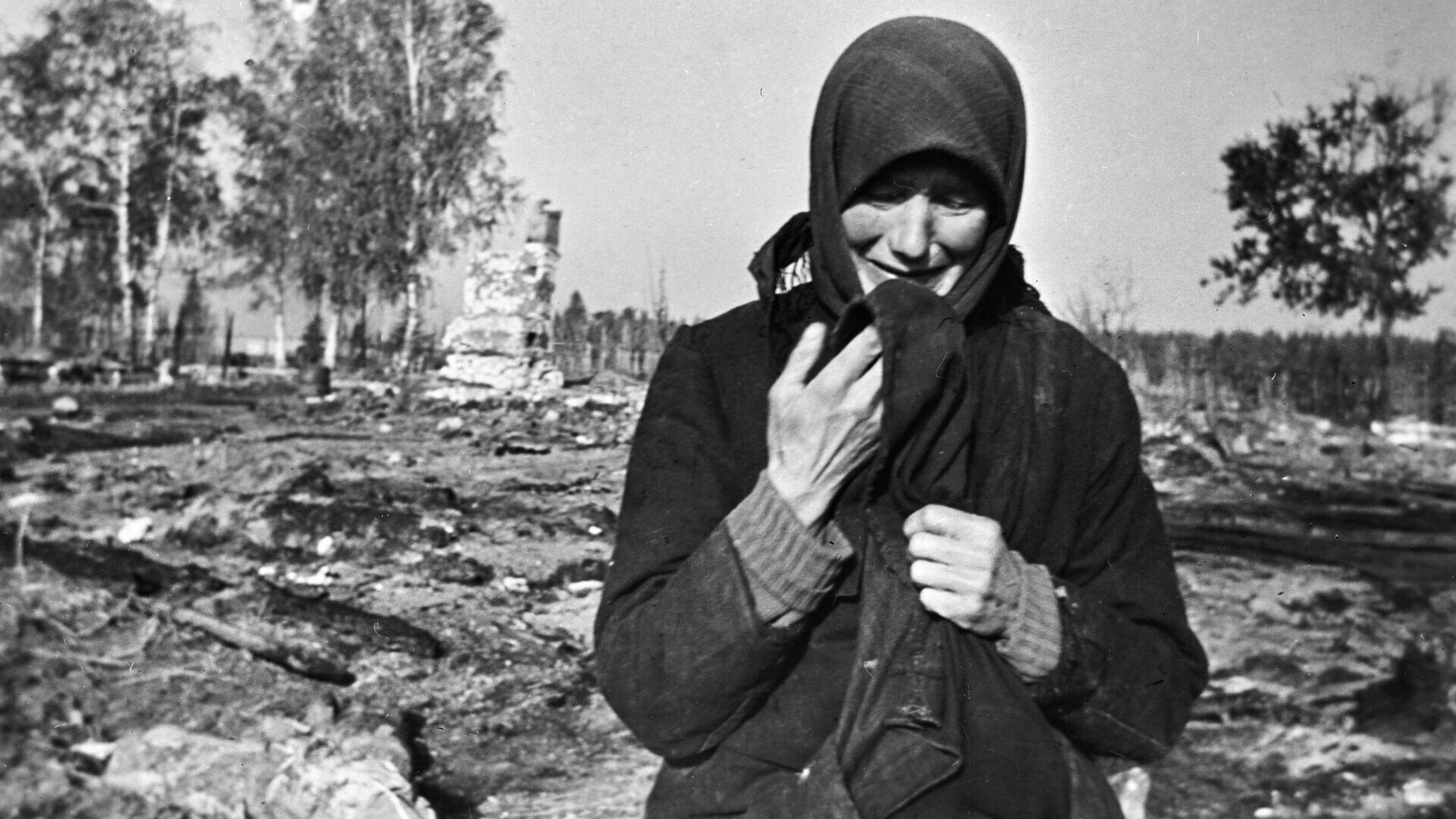 Seseorang perempuan menangis di reruntuhan desa asalnya yang dibakar oleh Nazi.