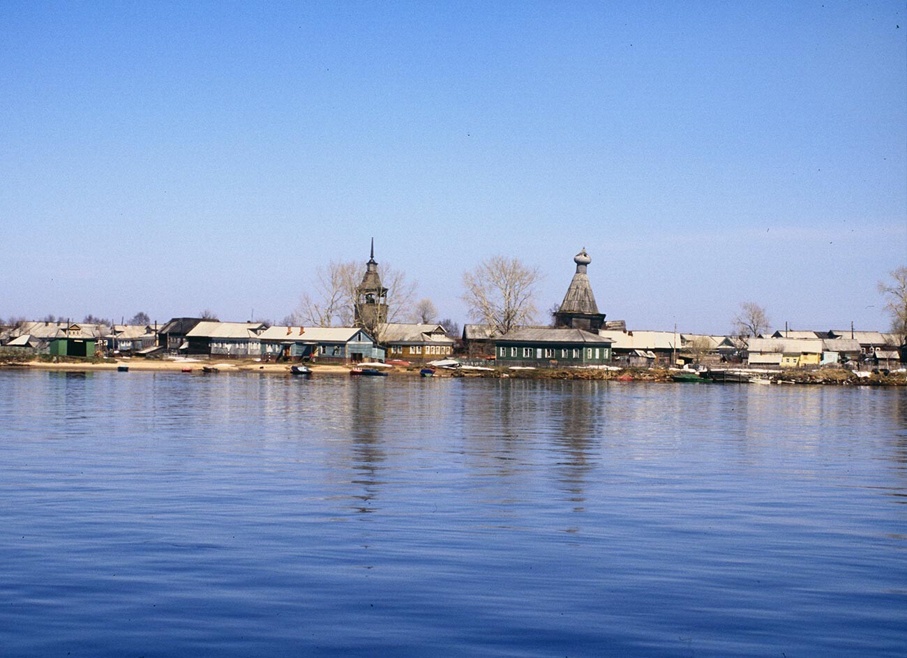 Konetsdvorye (in delta of Northern Dvina near Arkhangelsk). Background: wooden houses with bell tower & log Church of St. Nicholas, south view. May 21, 2000