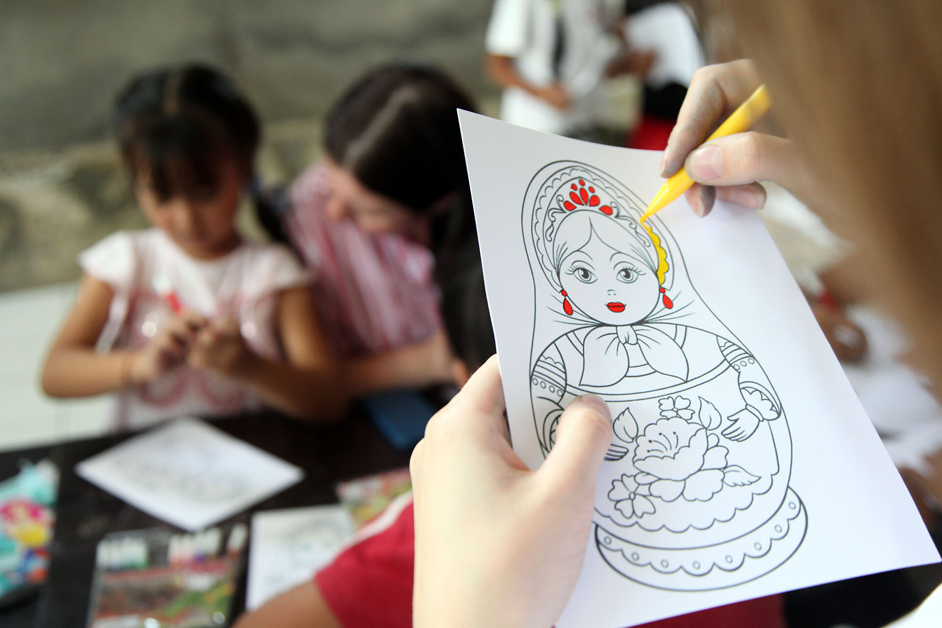 Seorang anak mewarnai gambar boneka khas Rusia, matryoshka.