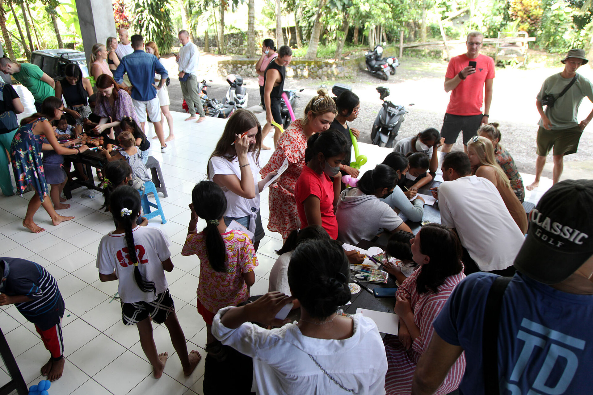 Para sukarelawan mendampingi anak-anak dalam acara bakti sosial.