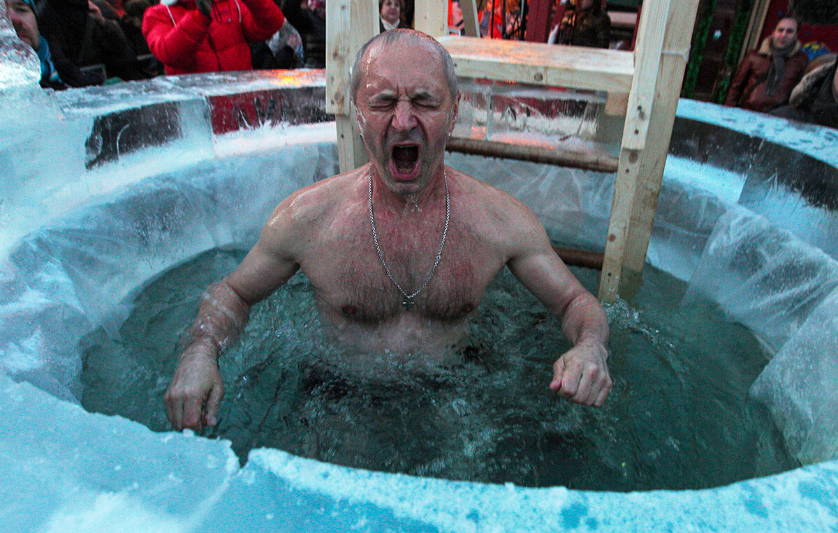 ロシア正教会の公現祭に氷水の穴に身を浸す男性