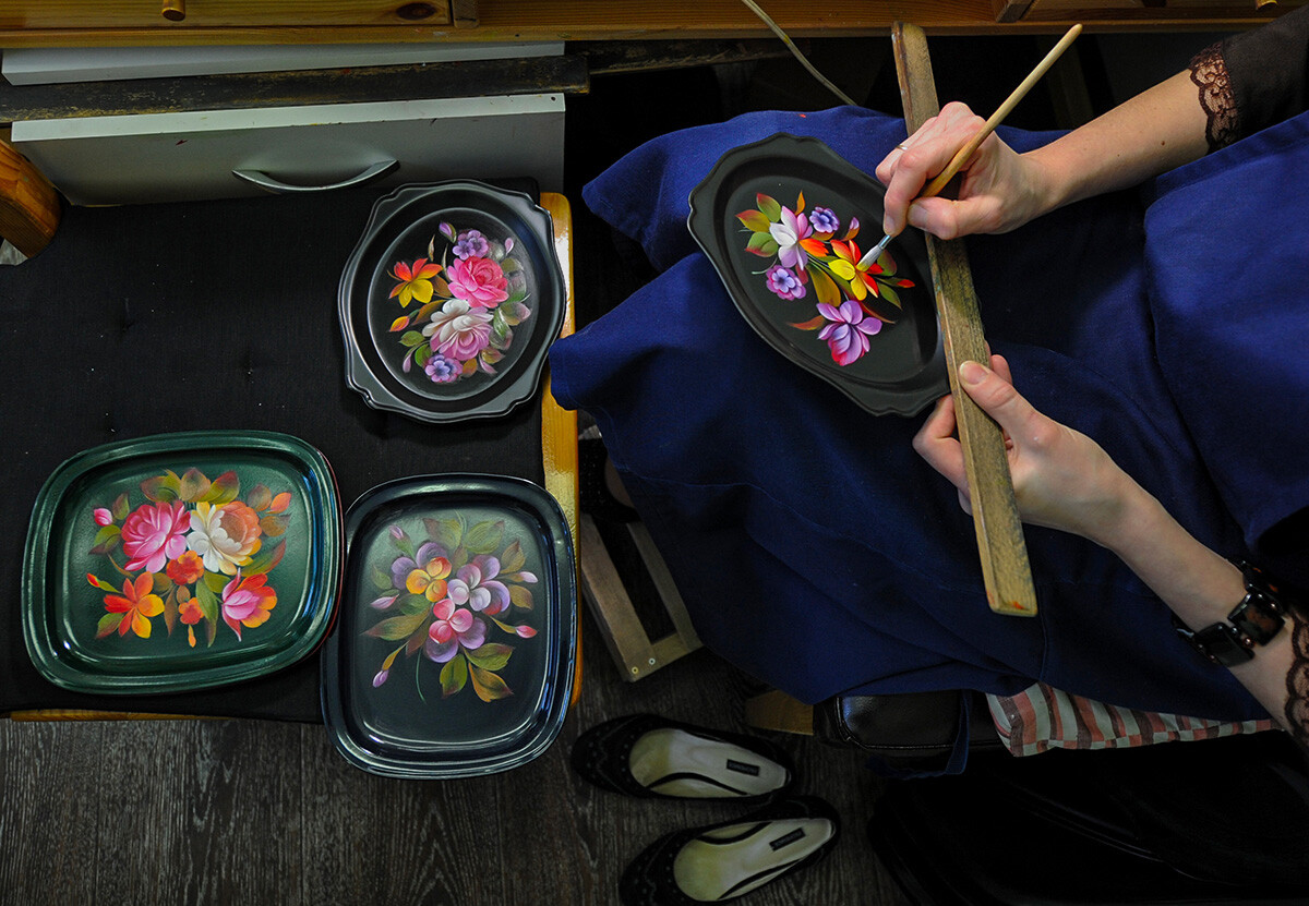 Ein Künstler bemalt Tabletts in der Fabrik für dekorative Malerei in Schostowo.