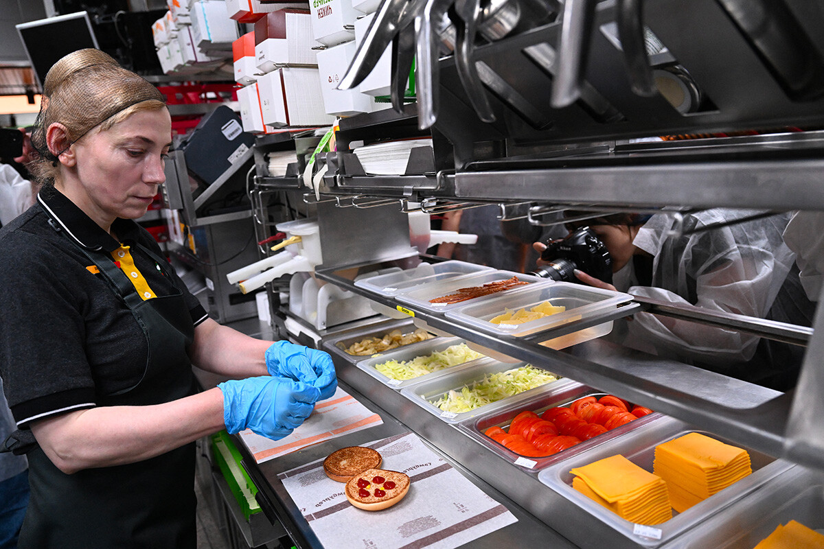 Ein Angestellter bereitet einen doppelten Cheeseburger in der russischen Version eines ehemaligen McDonald's-Restaurants vor der Eröffnungsfeier in Moskau am 12. Juni 2022 zu. 