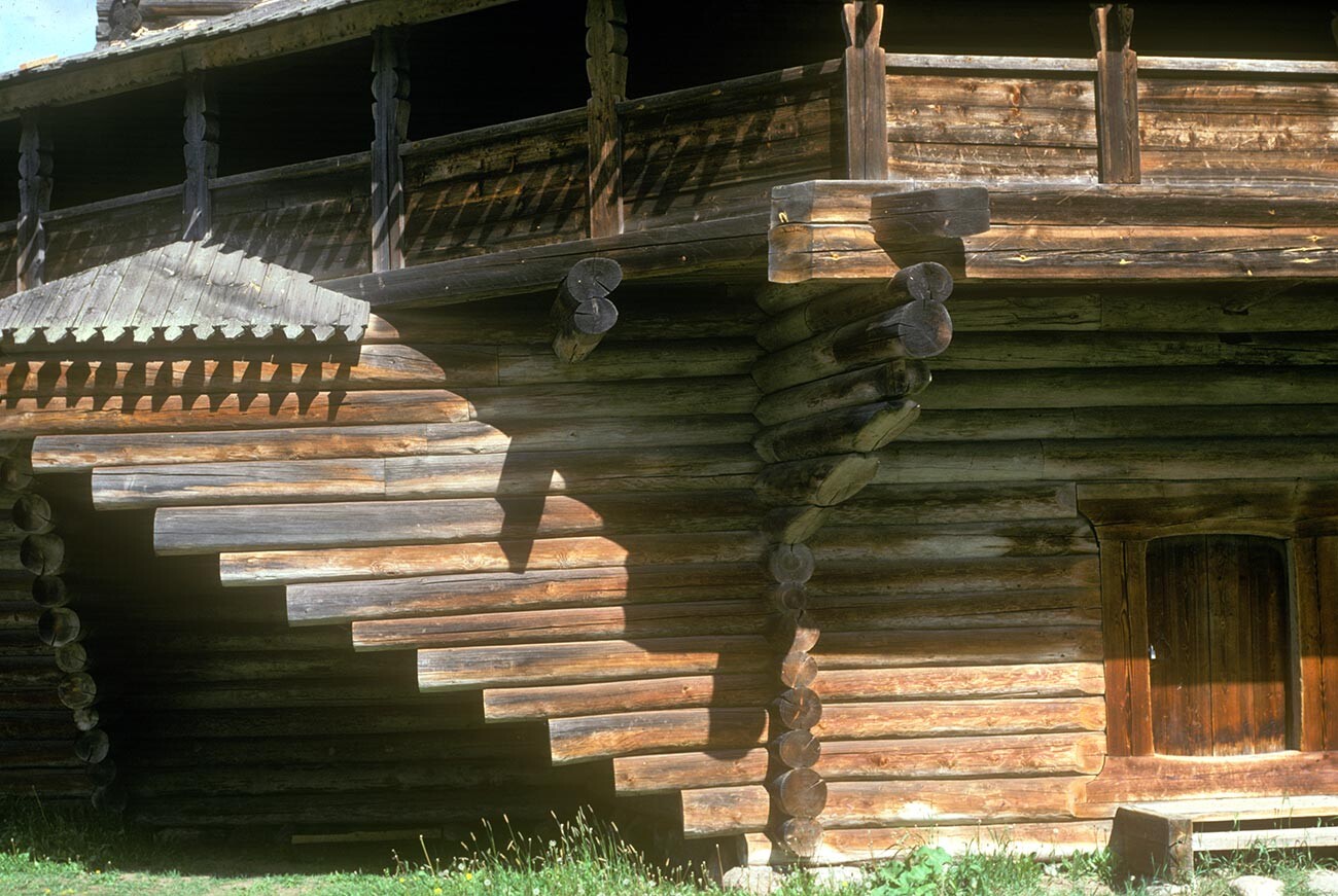Vitoslavlitsy. Church of the Nativity of the Virgin, from the village of Peredki. View of southwest corner with logs cantilevered to support the gallery. May 20, 1990