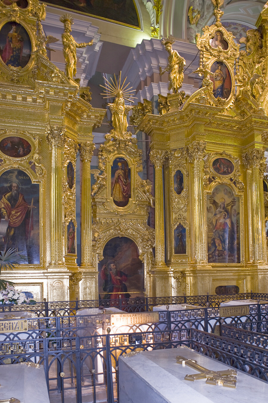 Gilded icon screen, left side with large icons of St. Paul (far left) & Mary enthroned with Christ Child. Foreground: royal sarcophagi (from left): Paul I, his wife Maria Feodorovna, Alexander I, his wife Elizabeth Alekseevna; near foreground: Nicholas I, his wife Alexandra Feodorovna.  June 7, 2015