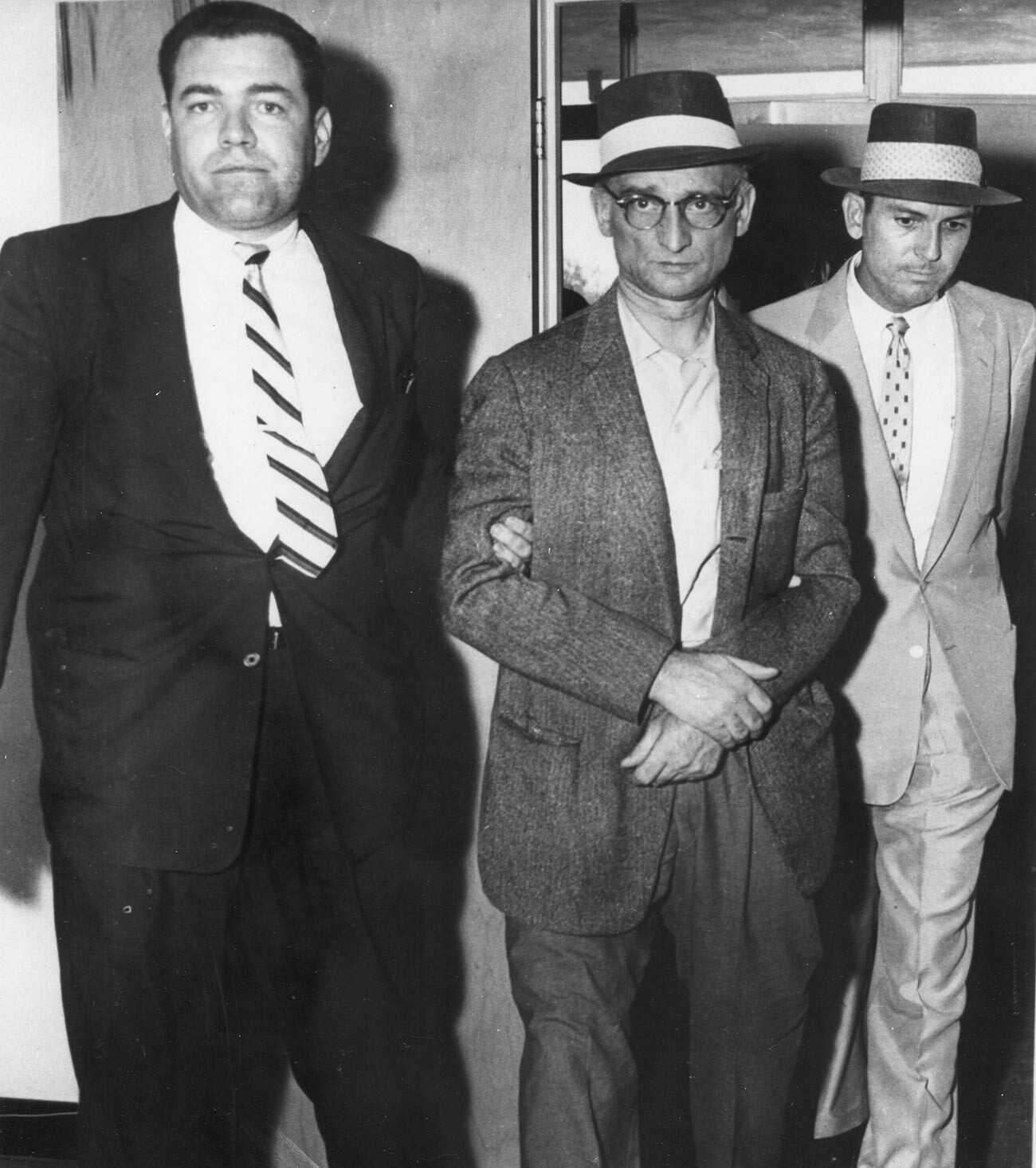 Osumljeni ruski vohun Rudolph Abel (znan tudi kot William August Fisher), v sredini, ob spremstvu ameriških policistov prihaja na sodišče, kjer ga obtožijo vohunstva, New York, New York, julij 1957. 