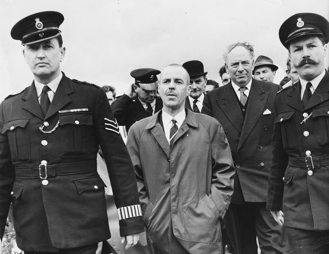 Greville Wynne scortato da un poliziotto dopo il rientro in patria dall'Unione Sovietica, all'aeroporto di Northolt, Inghilterra, 22 aprile 1964